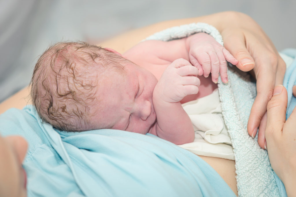 Young beautiful woman with a newborn baby after birth