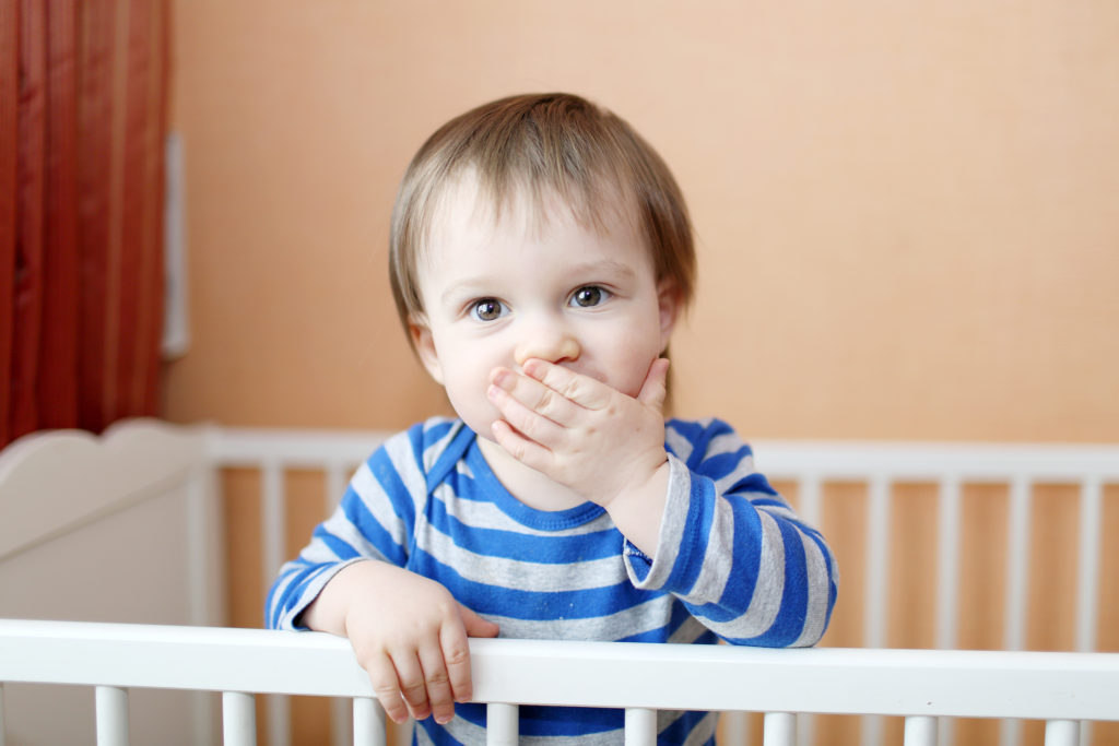 16 months baby keeps silent standing in white bed