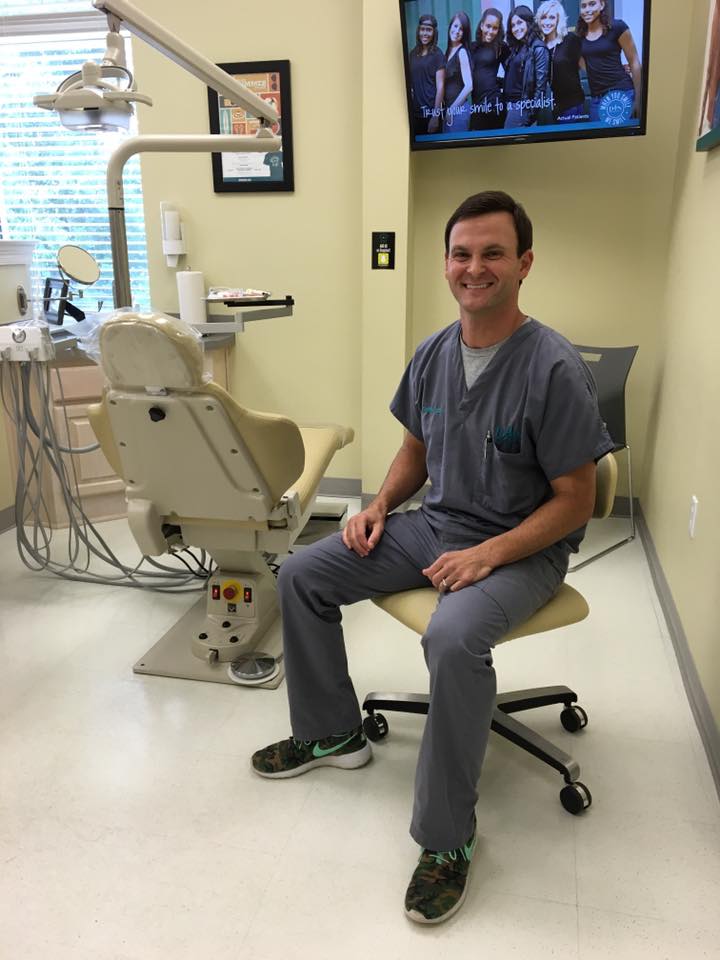 orthodontist sitting in a chair next to his exam chair