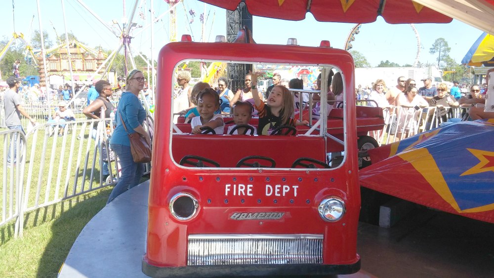 Three little girls ride in a giant plastic fire truck ride at the St. Tammany Parish Fair. 